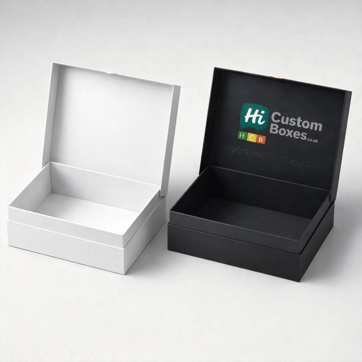 An open white presentation box shown next to an open black branded box for studio headsets. class=